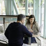 Founder meeting an early customer over a laptop at a cafe table