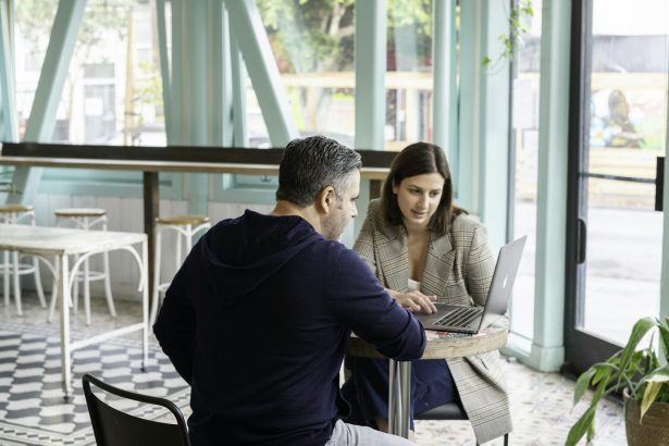 Founder meeting an early customer over a laptop at a cafe table