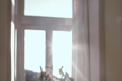 Steaming mug on a wooden table in front of a sunlit window