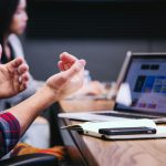 Consultant explaining a proposal to a client across a table with a laptop